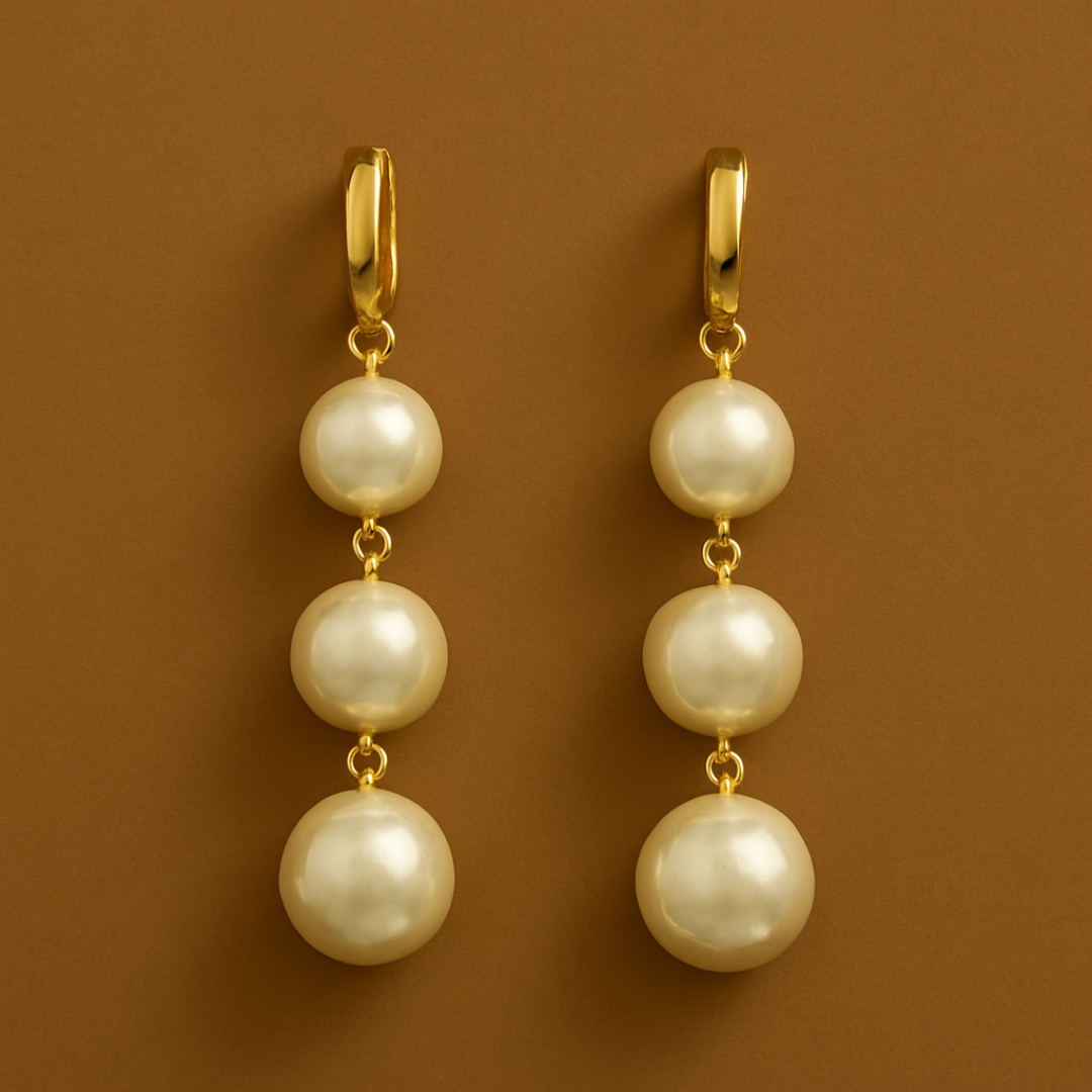 Gold Toned Drop Earrings featuring a line of three large, round white imitation pearls suspended from a polished gold hoop closure.